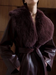 Model wearing a deep burgundy leather coat with a plush fur collar for Nour Hammour Fall Winter 25