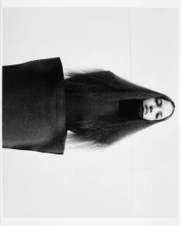 Portrait of a model with long dark hair framing the face against a plain white background for Dazed MENA.