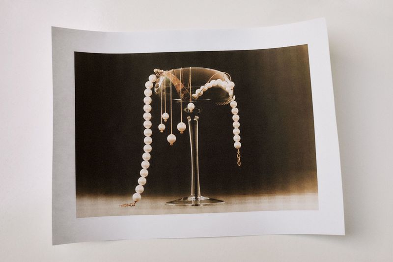 Elegant photo of pearl necklaces draped over a clear wine glass against a dark background, creating a sophisticated and luxurious aesthetic.