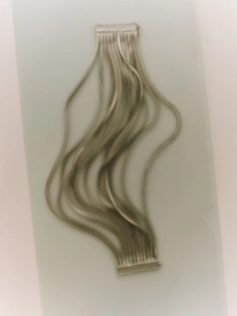 Close-up of silver hair extensions with wavy strands attached to clips, displayed against a muted background, beauty concept.