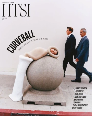 Magazine cover featuring a woman in a sculptural outfit reclining on a sphere, with two men in suits walking in the background.
