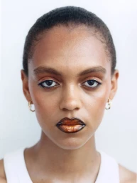 Close up portrait of a woman with metallic copper lips and dark eyeliner against a white backdrop for 72 Magazine