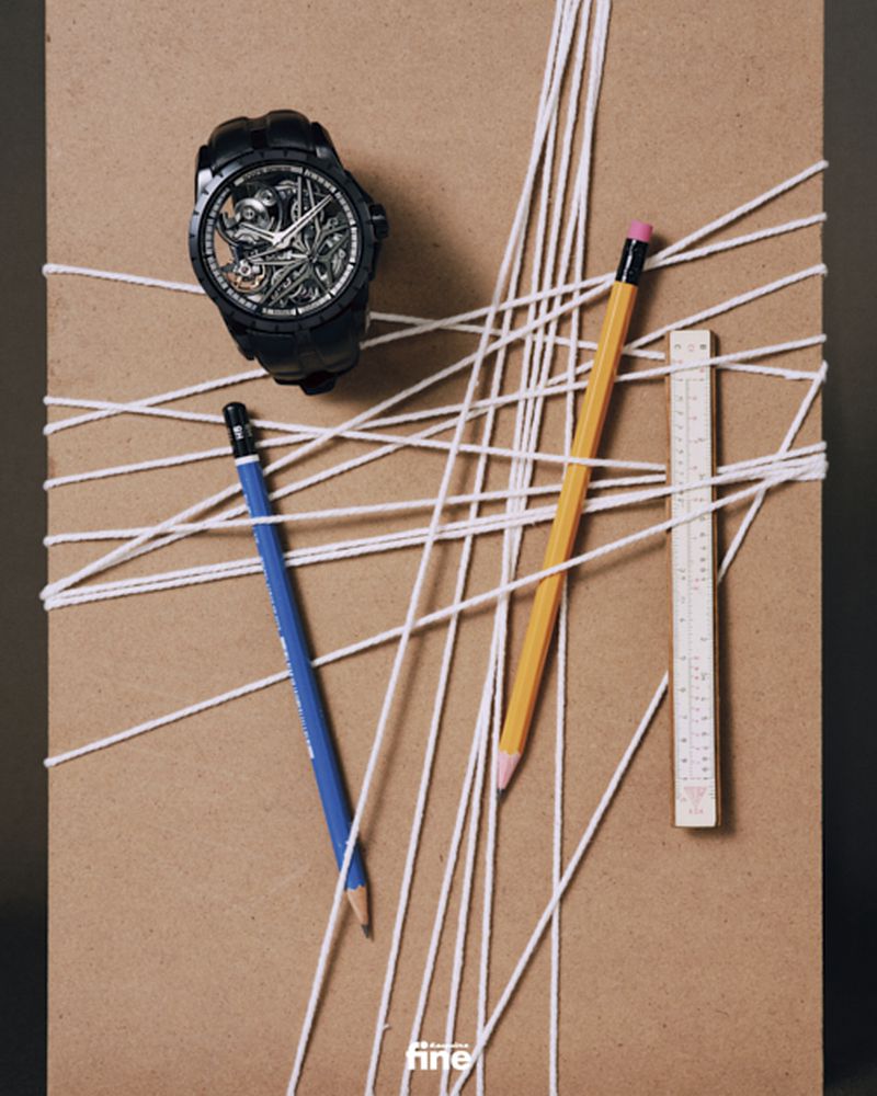 Wristwatch on brown surface with pencils and string. Stylish timekeeping accessory, studio shot.  Product photography for social media.