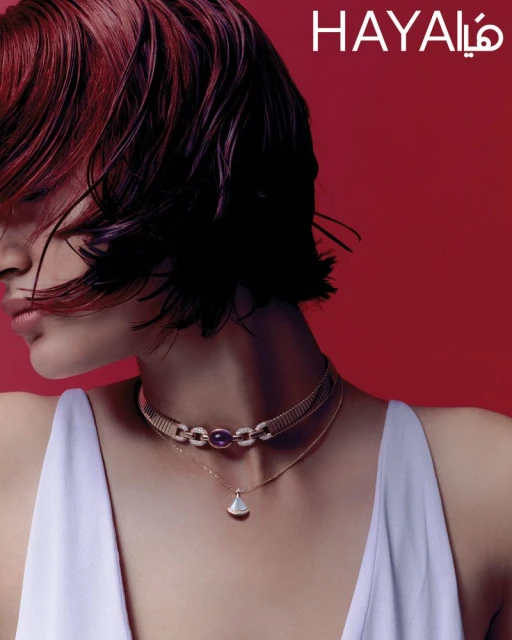 Close-up of an adult woman with burgundy hair wearing jewelry in front of a red background. Beauty shot for fashion and style.