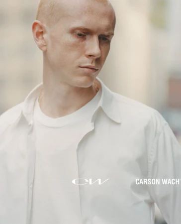 Close-up portrait of a young man with a shaved head wearing a white shirt and t-shirt for Carson Wach Spring/Summer 25 Campaign