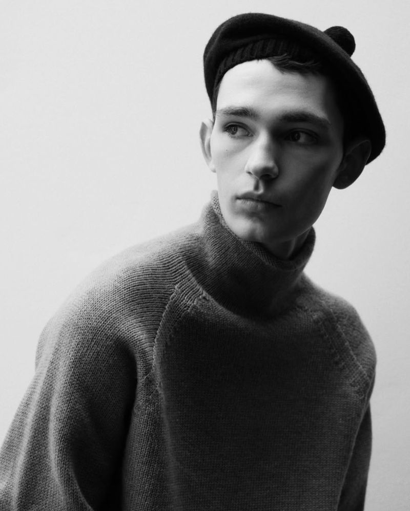 Monochrome portrait of a young adult man wearing a beret and turtleneck sweater, looking to the side against a plain light background.