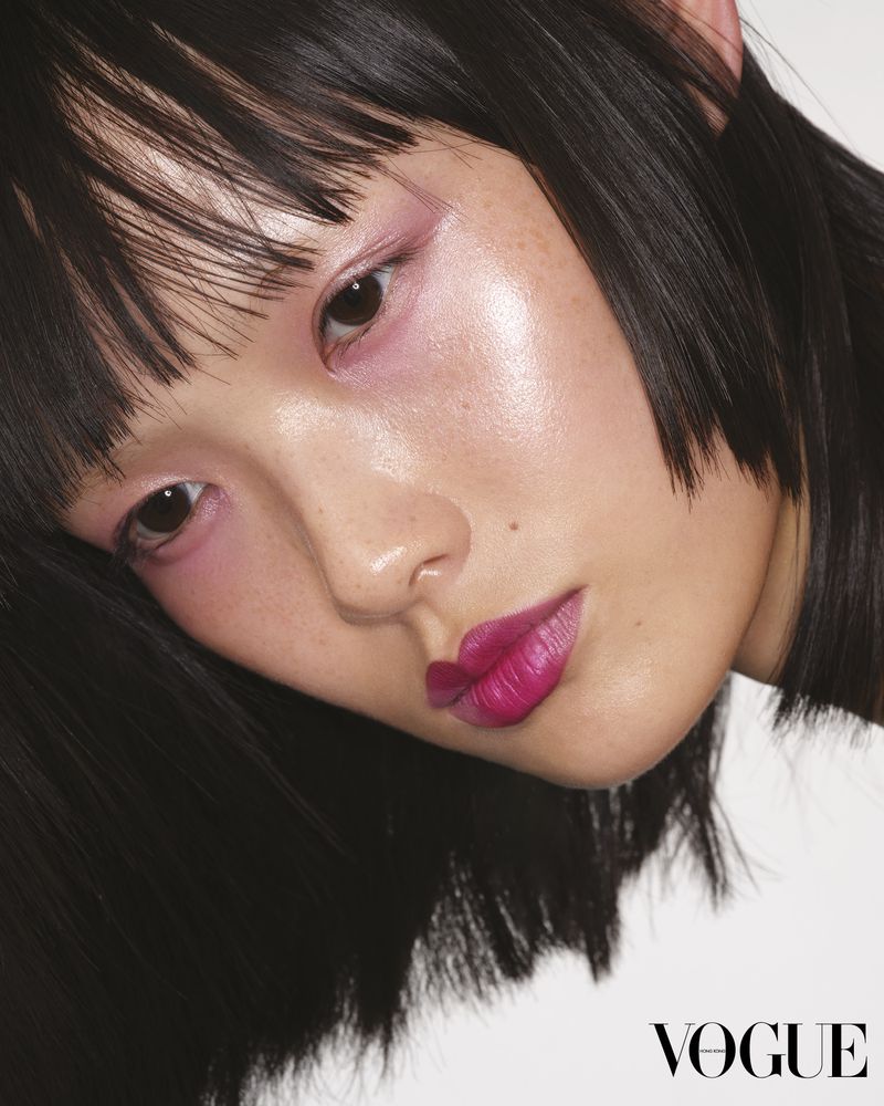Close-up beauty shot of a young adult Asian woman with black hair and pink makeup, featuring bright pink lips, set against a white backdrop.