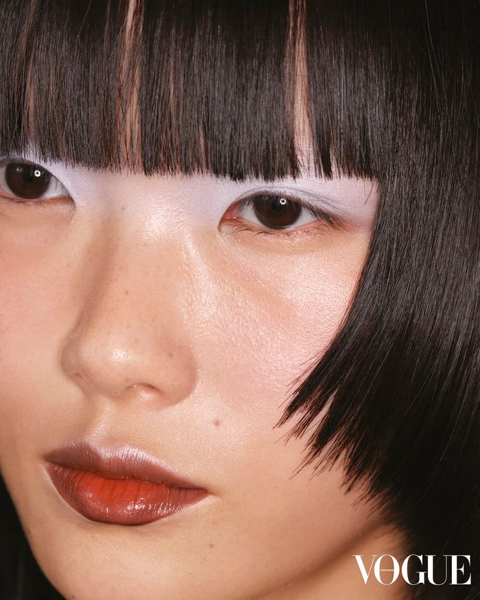 Close-up portrait of model Xie Chaoyu with blunt bangs and white eye makeup for Vogue Hong Kong Cast A Spell editorial by Benjamin Vnuk