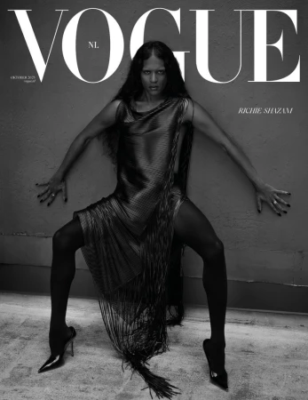 Black and white Vogue cover featuring a woman with long hair in a shimmering fringe dress posing with arms outstretched against a wall.