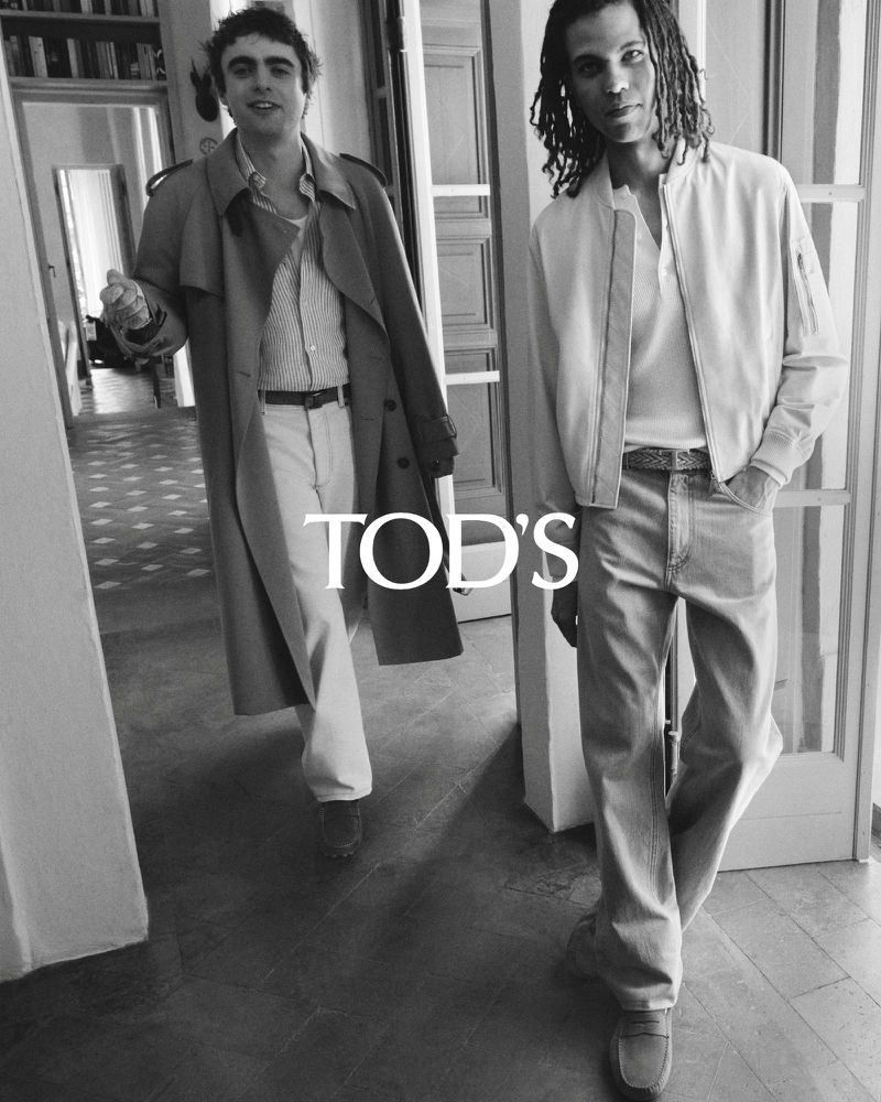 Two adult males model beige and white fashionable casual clothing in a bright indoor environment with natural light. TOD’S logo is displayed.