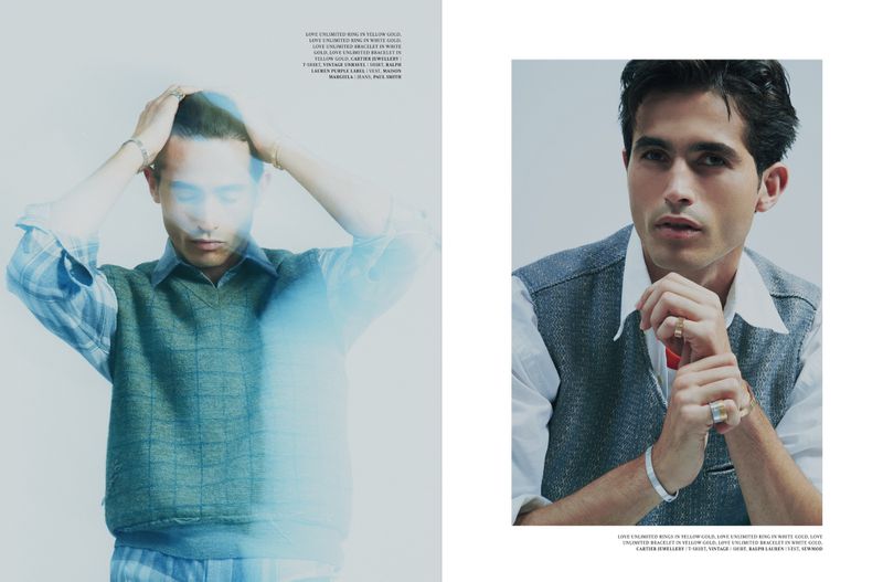 Editorial fashion shot of two adult men wearing knitted vests and bracelets against a studio backdrop with a shallow depth of field.