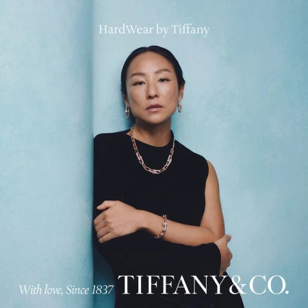 Elegant Asian woman showcases Tiffany & Co. HardWear jewelry against a textured blue backdrop, highlighting a necklace, earrings, and bracelet.