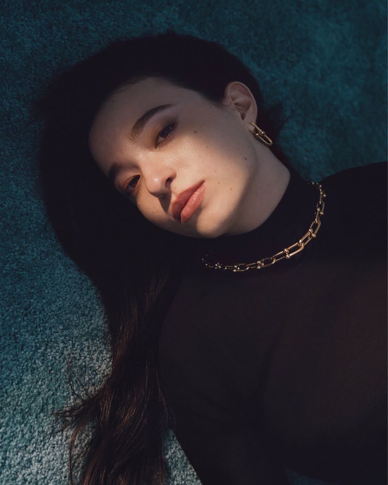 Close-up portrait of actor Mikey Madison wearing gold chain jewellery against a textured background for Tiffany and Co.