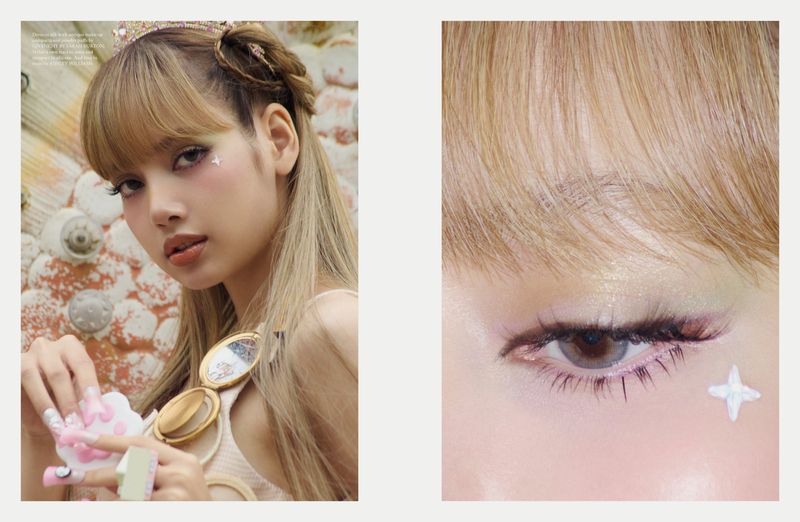 Close-up beauty shot of a woman with blonde hair, bangs, wearing a crown, cosmetic glitter, and pink nail art, indoors.