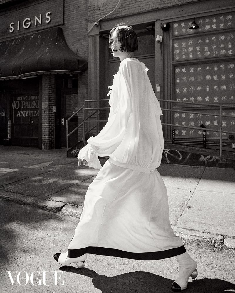 Model in a white dress walking down a city street for Vogue Hong Kong captured by Bridget Fleming