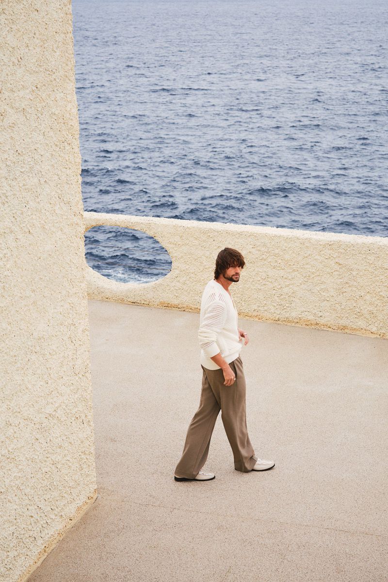 Man walking on a textured stone terrace overlooking the ocean for H&M Spring 2025 Menswear campaign