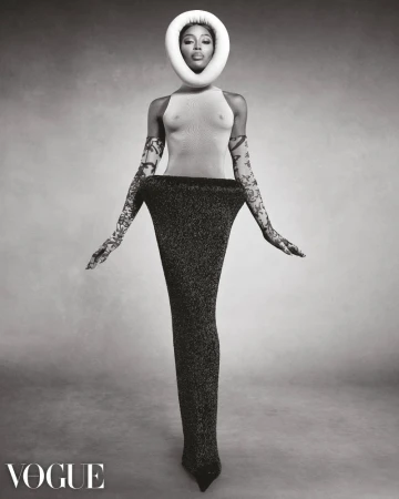 Striking black and white fashion portrait of Naomi Campbell with a unique halo headpiece, gloves, and gown. Vogue magazine logo is visible.