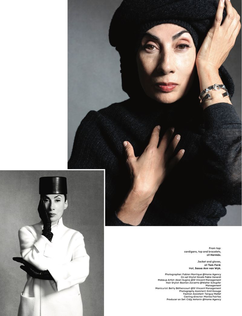 Close-up portrait of a woman with dark hair in a black beret and turtleneck, adorned with a silver bracelet, against a grey backdrop.