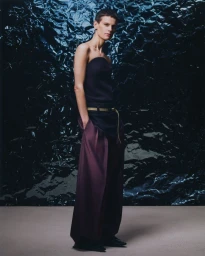 Saskia de Brauw posing in a dark strapless top and wide-leg trousers against a crinkled foil backdrop for BOSS PARADOX SS26.