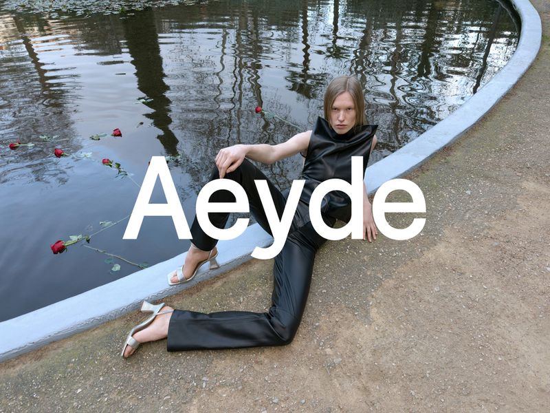 A fashion shot features a model in a black outfit sitting beside a pool with red roses. The image is branded with 'Aeyde' text.