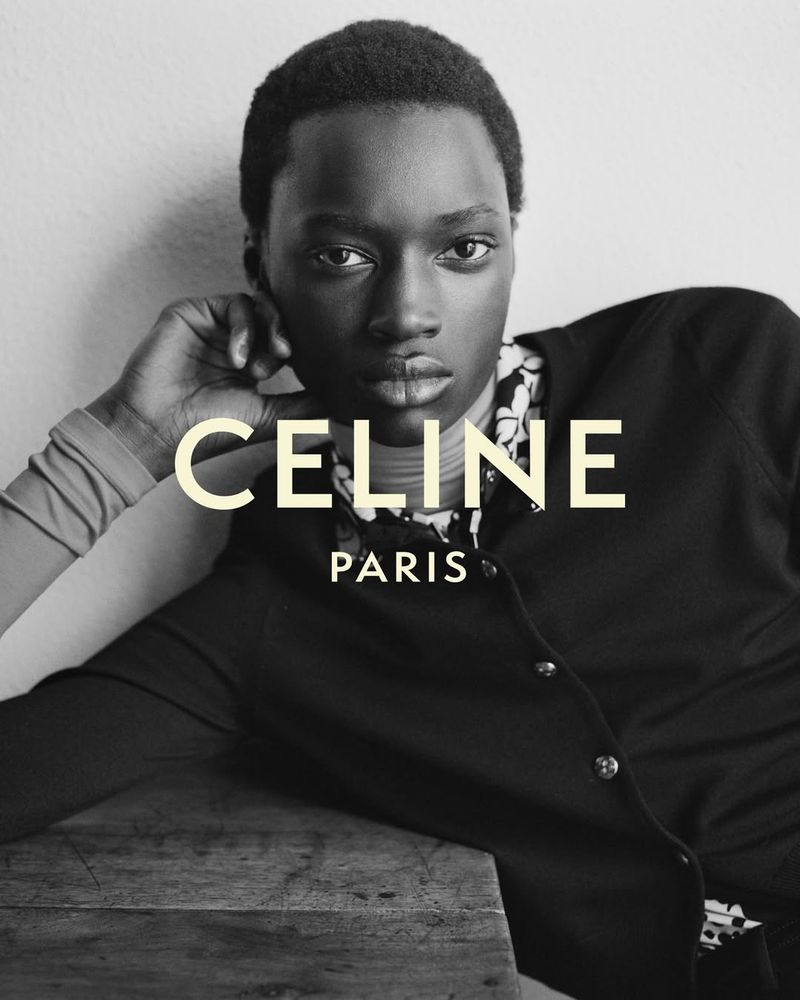 Portrait of a Black female model wearing a black cardigan and floral shirt against a white wall, with 'CELINE PARIS' text overlay.