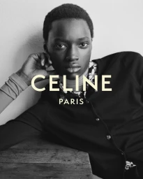 Black and white portrait of a Black male model in a dark buttoned cardigan resting his head on his hand for Celine.