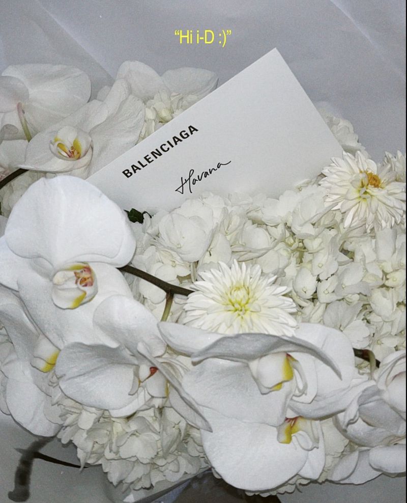 Floral arrangement featuring white orchids, chrysanthemums, and a Balenciaga branded card, creating a modern, elegant aesthetic.