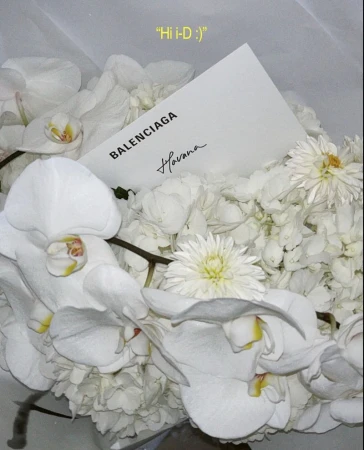 Floral arrangement featuring white orchids, chrysanthemums, and a Balenciaga branded card, creating a modern, elegant aesthetic.