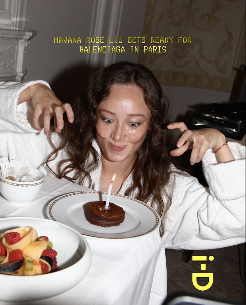 Woman in bathrobe poses playfully with a small cake and a candle on a white table; text overlay of magazine title and brand name.