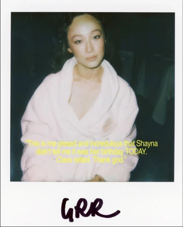 Portrait of a young adult woman in a white robe, captured in a candid polaroid-style photo with handwritten text below.