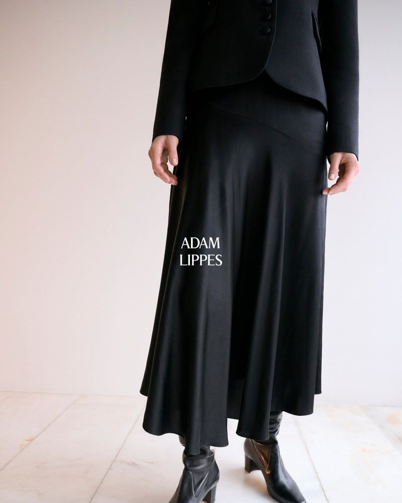 Black long skirt and jacket outfit displayed on a model against a neutral background. The brand logo 'ADAM LIPPES' is shown.