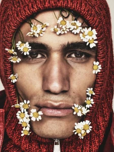 Close-up portrait of a man wearing a red knit balaclava framed with small white daisies.