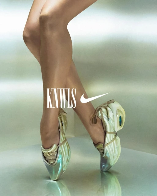Close-up shot of woman's legs and feet wearing futuristic, high-fashion Nike ballet shoes, set against a gradient light-silver background. 