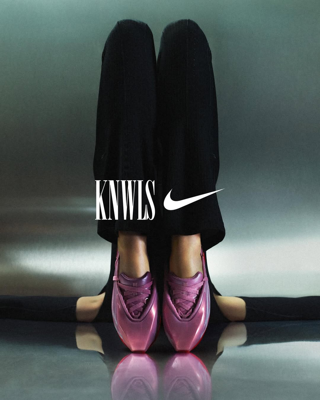 Close-up studio shot of legs and feet wearing pink ballet slipper style sneakers, featuring KNWLS and Nike logos on a gray background.