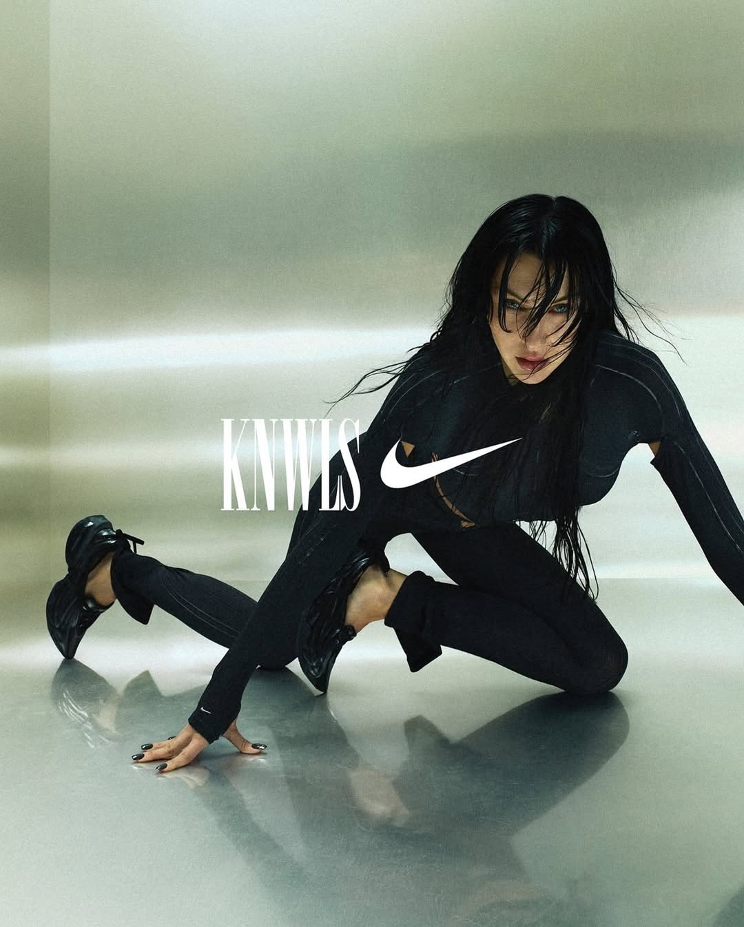 Athletic woman in black sportswear poses on reflective surface with logo and brand text. Fashion forward fitness apparel for women.
