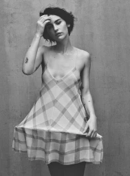 Gracie Abrams wearing a patterned slip dress against a textured concrete wall, photographed by Daniel Jackson for Vogue Espana.