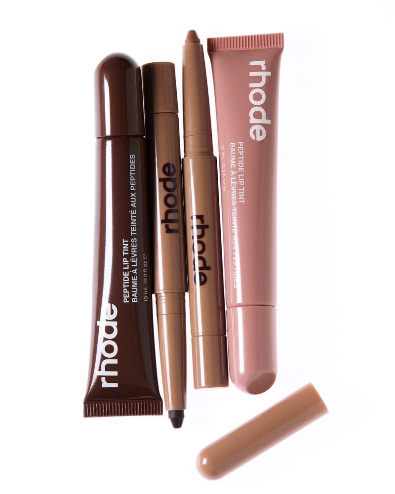 Rhode skincare product tubes and containers in brown and beige tones displayed on a white surface, promoting beauty and self-care.