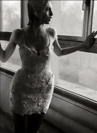 Woman in lace dress and bonnet looking out window in black and white. Indoor fashion portrait with natural light and window.