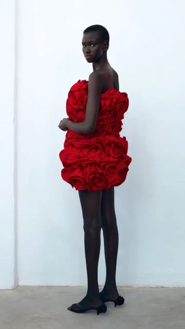 Model in a red rose-textured dress, full shot against a white backdrop, studio lighting, fashion editorial, elegant, and captivating.