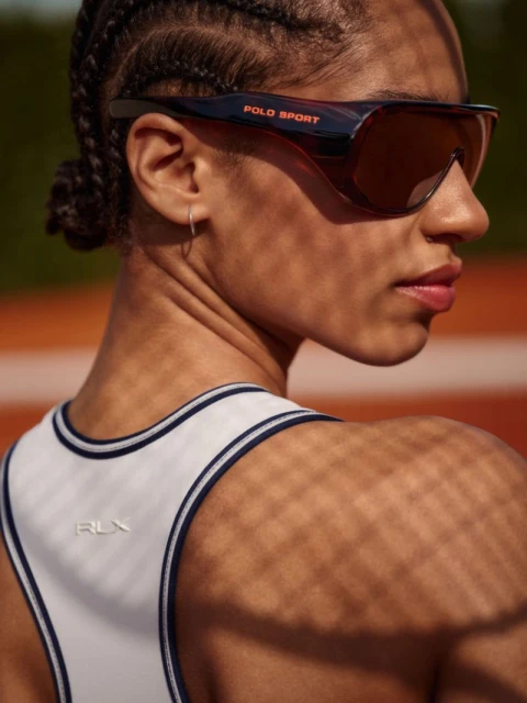 Athletic woman wearing POLO SPORT sunglasses and RLX top, seen from behind on an orange track. Close-up on face and upper back.