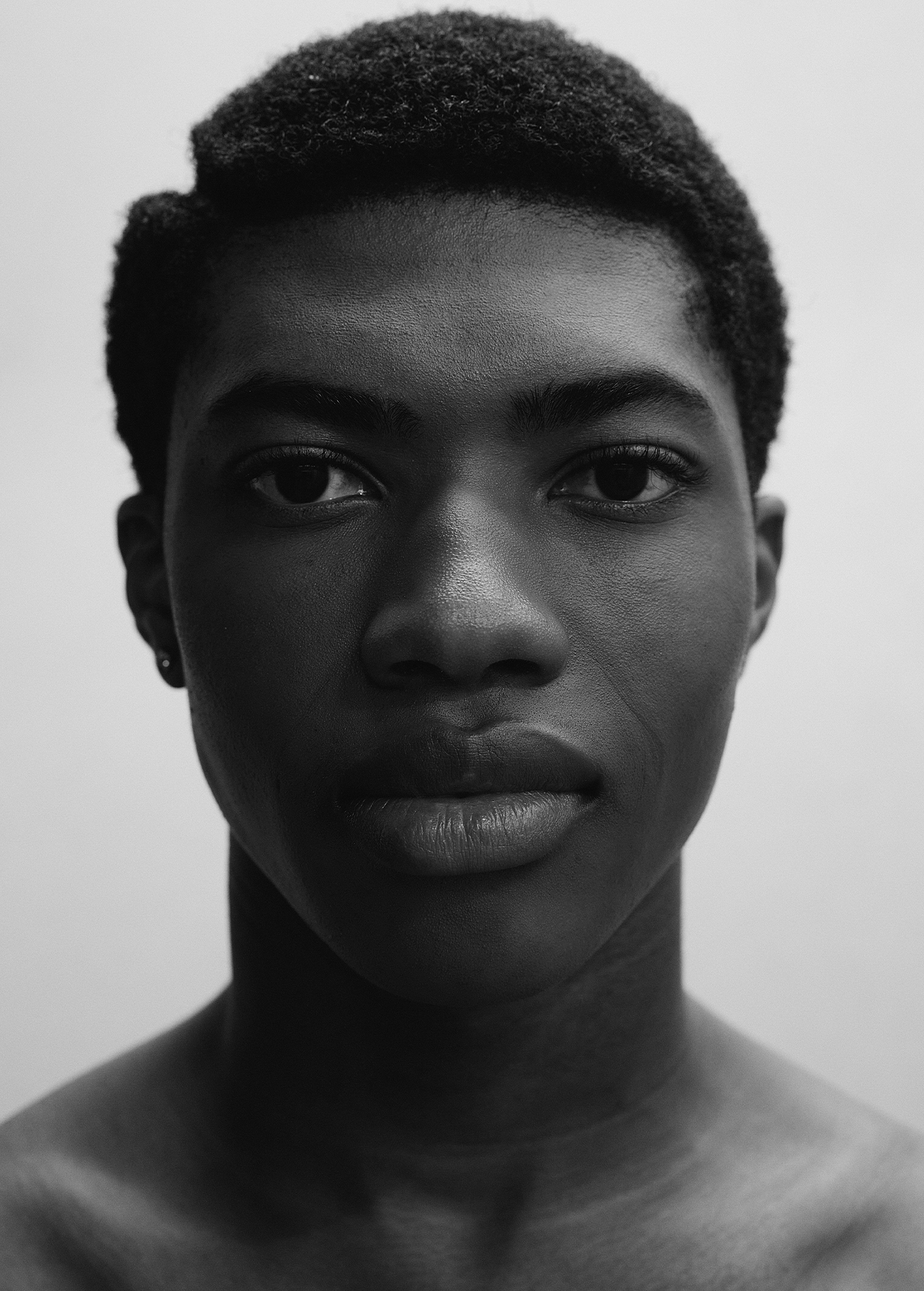 Monochrome portrait of a young Black man with short hair, showcasing a serious expression against a plain background.