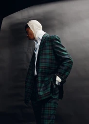 Man wearing a green plaid suit and white head covering against a dark seamless backdrop for Icon Magazine Australia.