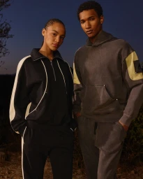Two models standing outdoors at dusk wearing dark athletic apparel by Moose Knuckles, photographed by Louise and Maria Thornfeldt.