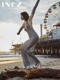 Model Megan Irminger in a sparkly silver dress on a sandy beach near a pier with a Ferris wheel for Inez Spring 2025.