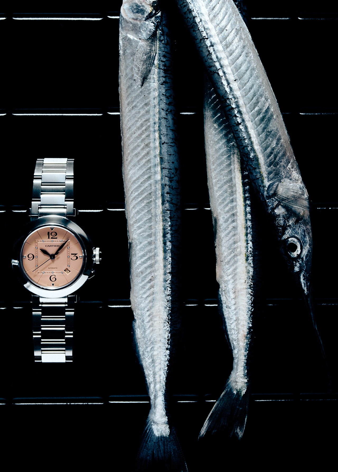 Still life with a luxury wristwatch on a metal grate, arranged with three fresh, silvery fish for a unique composition.