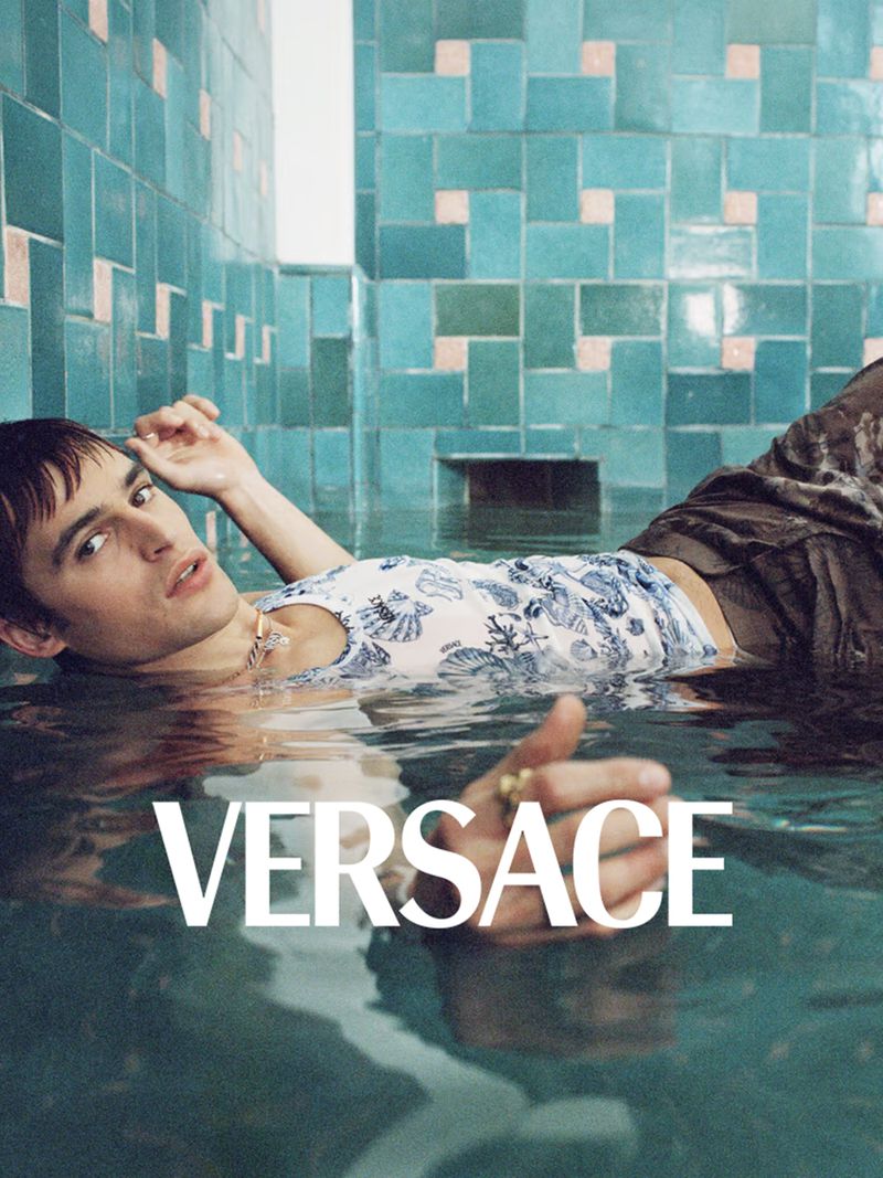 Model floating in a tiled pool wearing a printed top for the Versace La Vacanza 2025 campaign photographed by Zoë Ghertner