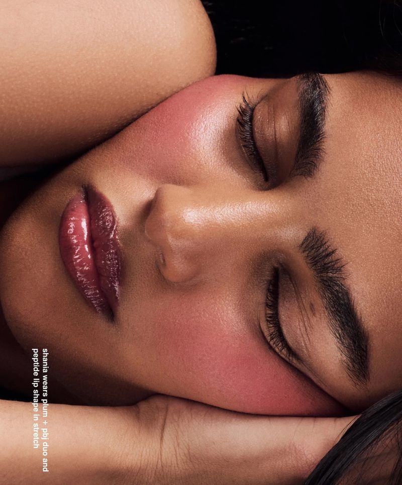 Close-up beauty shot of a resting adult woman with closed eyes. Her face is softly illuminated, highlighting her skin and makeup.
