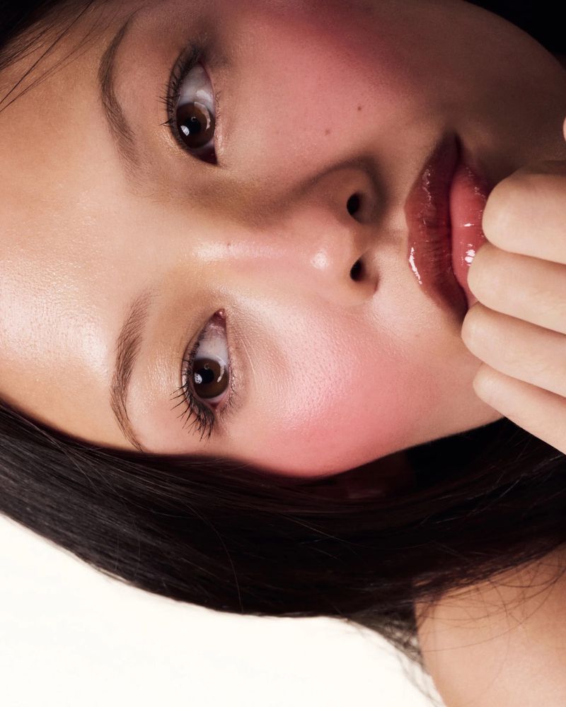 Close-up beauty portrait of a model with glossy lips and flushed cheeks against a clean white background
