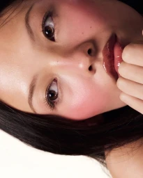 Close-up beauty portrait of a model with glossy lips and flushed cheeks against a clean white background