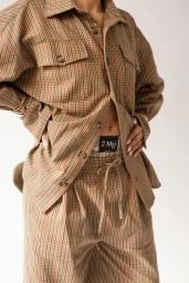 Model wearing a brown plaid button-up shirt and matching drawstring trousers against a white seamless background
